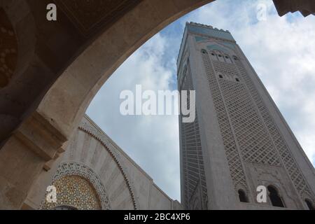 Le plus grand minaret du monde, à 210 m de haut, se trouve à la mosquée Hassan II, Casablanca, au Maroc, que l'on voit ici à travers l'une des arcades de la structure moderne. Banque D'Images