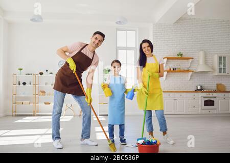 Une famille heureuse nettoie la chambre dans la maison. Mère père et petite fille enfant laver dans des gants tout en s'asseoir sur le sol souriant joyeux. Hygiène W Banque D'Images