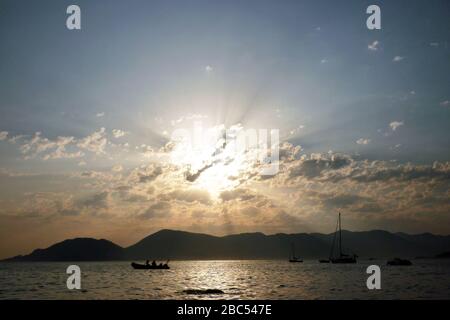 Les rayons du soleil traversent les nuages au coucher du soleil près de l'océan en Ligurie Banque D'Images