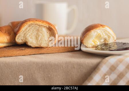 Croissant avec café, chocolat, thé pour le petit déjeuner. Table rustique le matin. Confiture de prunes pour pains. Loisirs ruraux. Banque D'Images