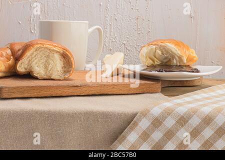 Croissant avec café, chocolat, thé pour le petit déjeuner. Table rustique le matin. Confiture de prunes pour pains. Loisirs ruraux. Banque D'Images