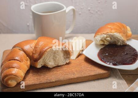 Croissant avec café, chocolat, thé pour le petit déjeuner. Table rustique le matin. Confiture de prunes pour pains. Loisirs ruraux. Banque D'Images