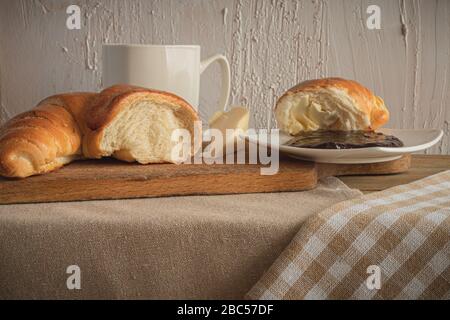 Croissant avec café, chocolat, thé pour le petit déjeuner. Table rustique le matin. Confiture de prunes pour pains. Loisirs ruraux. Banque D'Images