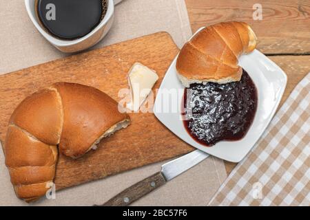 Croissant avec café, chocolat, thé pour le petit déjeuner. Table rustique le matin. Confiture de prunes pour pains. Loisirs ruraux. Banque D'Images