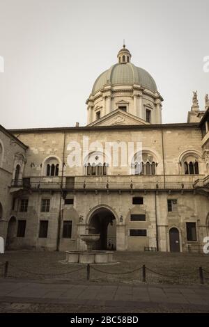 Brescia, Italie - 1 août 2018: La vue de la fontaine dans la cour intérieure du palais médiéval Palazzo del Broletto avec dôme de la nouvelle cathédrale sur b Banque D'Images