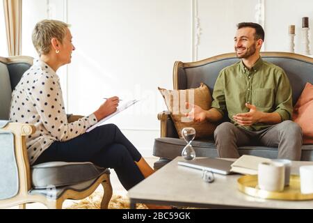 Homme souriant et souriant à sa psychanalyste féminine Banque D'Images