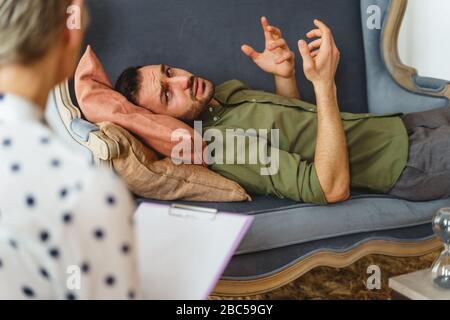 Triste jeune homme parlant à son psychanalyste Banque D'Images