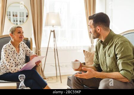 Psychothérapeute féminin souriant à sa patiente masculine Banque D'Images