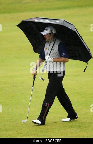 Lee Westwood, l'Angleterre, abrite la pluie lorsqu'il descend le 18ème fairway Banque D'Images