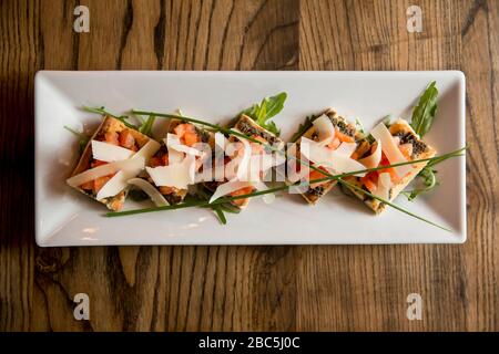 Bruschetta avec pesto olive et ail, avec tomate cerise et feuilles de parmesan dans la plaque Banque D'Images