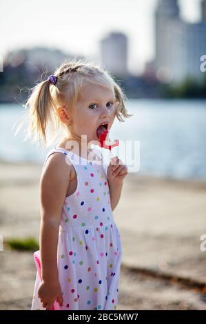 Une petite fille qui mange de la lollipop dans le parc Banque D'Images