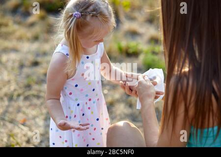 Maman essuie la paume de sa fille avec une serviette humide. Maman se soucie de sa petite fille. Protection contre la pandémie du virus Corona en se lavant les mains Banque D'Images