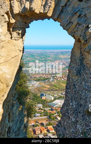 Vue à travers l'arche du Col des Sorcières de Saint-Marin à la vallée Borgo Maggiore de l'Emilie-Romagne en Italie Banque D'Images