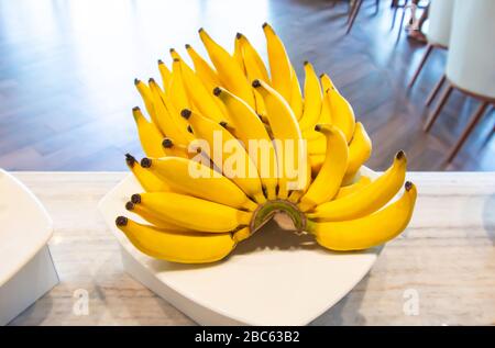 Lebmuernang banane mis sur beaucoup et beau jaune dans le plat blanc. Banque D'Images