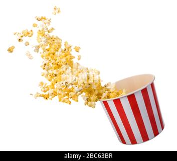 Popcorn volant à partir d'un seau à rayures en papier isolé sur fond noir avec chemin de découpe. Concept de cinéma ou de télévision. Banque D'Images