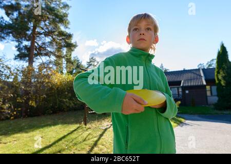 Jeune beau garçon jouant Frisbee dans la cour avant Banque D'Images