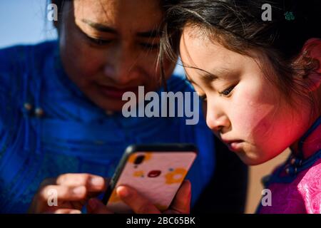 (200403) -- ALXA, 3 avril 2020 (Xinhua) -- ce Geng (R) se prépare à prendre des cours en ligne avec l'aide de sa mère dans Alxa Left Banner, région autonome de la Mongolie intérieure nord, 1er avril 2020. Ce Geng, un quatrième niveleur de 9 ans d'une école mongole à Alxa Left Banner, s'est déplacé ici avec ses parents pour s'occuper des moutons comme le berger qu'ils avaient embauché d'autres provinces n'a pas pu revenir en raison de l'éclosion de COVID-19. Le ranch de la famille est situé près de la frontière entre la Chine et la Mongolie dans la partie nord d'Alxa, à plus de 6 heures de route du centre-ville d'Alxa Left Banner. Le rocailleux Banque D'Images