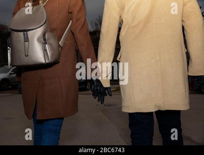 Couple portant des gants en nitrile noirs marchant dans la rue et tenant leurs mains mise au point sélective Banque D'Images