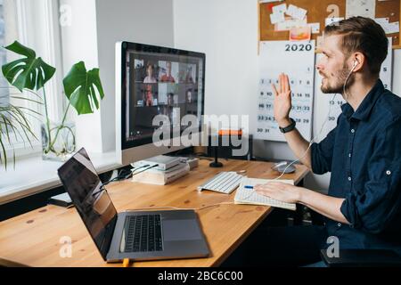 Riga, Lettonie - 28 mars 2020: Jeune homme ayant un zoom appel de visioconférence par ordinateur. Bureau à domicile. Restez à la maison et travaillez à partir du concept de maison Banque D'Images