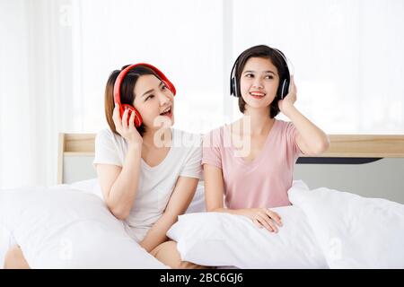 Deux femmes asiatiques heureuses portent un casque et apprécient les musiques ou les chansons qu'elles aiment dans la chambre. Banque D'Images