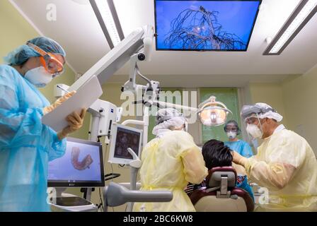 Dresde, Allemagne. 03ème avril 2020. ILLUSTRATION - le dentiste Conrad Kühnöl (r) traite un patient corona dans sa pratique dentaire (scène posée) avec visière, masque respiratoire FFP3 et robe antivirale avec ses assistants dentaires. Crédit: Robert Michael/dpa-Zentralbild/dpa/Alay Live News Banque D'Images