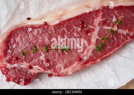 Gros morceau entier de viande de boeuf brute, stripline sur papier parchemin blanc Banque D'Images