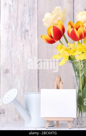 Fleur de tulipe dans un vase en verre avec cadre photo décor sur une table en bois mur d'arrière-plan à la maison, gros plan, concept de la fête des mères. Banque D'Images