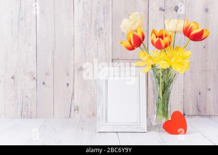 Fleur de tulipe dans un vase en verre avec cadre photo décor sur une table en bois mur d'arrière-plan à la maison, gros plan, concept de la fête des mères. Banque D'Images