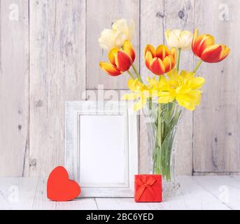Fleur de tulipe dans un vase en verre avec cadre photo décor sur une table en bois mur d'arrière-plan à la maison, gros plan, concept de la fête des mères. Banque D'Images