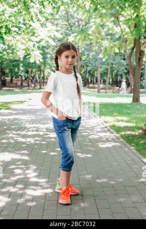 petite fille souriante modèle en chemise blanche posant dans le parc Banque D'Images