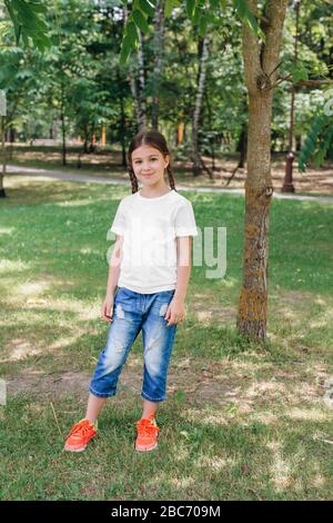 petite fille souriante modèle en chemise blanche posant dans le parc Banque D'Images