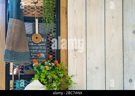 Plantez à l'intérieur d'un sac fourre-tout et d'un tablier de cuisine décoration accrochée sur un mur de retenue en acier et un mur en bois. Banque D'Images