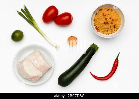 Des ingrédients frais pour faire du merlu cajun, avec des légumes et du couscous sur un fond blanc Banque D'Images