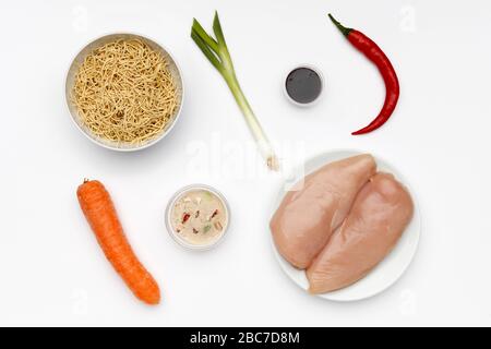 Ingrédients frais pour faire de la viande de poulet, avec des légumes et des nouilles sur un fond blanc brillant Banque D'Images