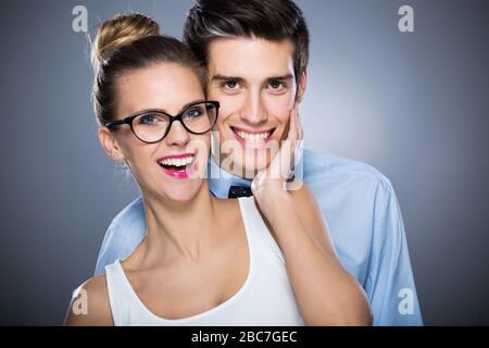 Jeune couple debout sur fond gris Banque D'Images