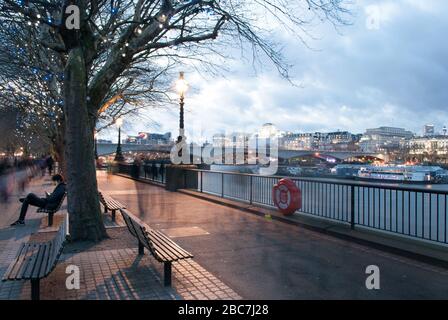 Adolescent garçon Sat sur banc sur smartphone sur South Bank London Banque D'Images