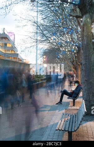 Adolescent garçon Sat sur banc sur smartphone sur South Bank London Banque D'Images