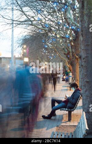 Adolescent garçon Sat sur banc sur smartphone sur South Bank London Banque D'Images