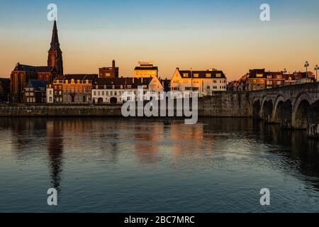 La rivière Maas / Meuse dans le centre de Maastricht avec vue sur la brasserie de bière Ridder pendant le coucher du soleil avec un ciel incroyable plein de couleur. Banque D'Images