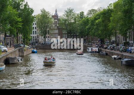 Amsterdam, Pays-Bas -- 29 juillet 2019. Les gens en petits bateaux prennent le temps de faire une croisière sur les nombreux beaux canaux d'Amsterdam un après-midi d'été. Banque D'Images