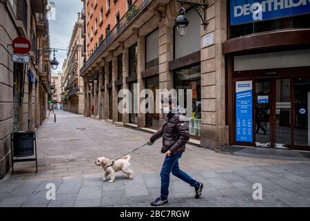 Barcelone, Espagne. 02 avril 2020. Un homme portant un masque de protection marche avec son animal de compagnie le long d'une rue déserte pendant le 19ème jour de la maison confinement et distanciation sociale à Barcelone.en raison de la contagion du Covid-19, les rues sont pratiquement vides et seules les activités commerciales essentielles sont maintenues ouvertes. Crédit: SOPA Images Limited/Alay Live News Banque D'Images
