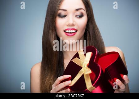Woman holding heart-shaped box Banque D'Images