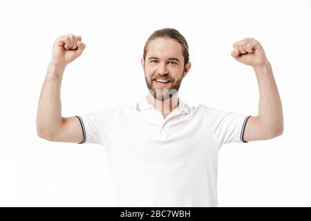 Photo de l'homme barbu heureux et émotif posant isolé sur fond de mur blanc faire le geste du gagnant. Banque D'Images