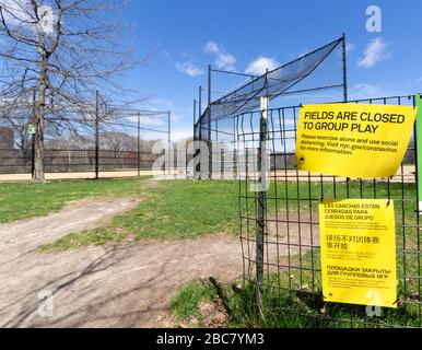 Les panneaux jaunes en sept langues indiquent au public que le terrain de baseball de Central Park est fermé pour jouer en groupe en raison du coronavirus ou de la pandémie de covid-19 Banque D'Images