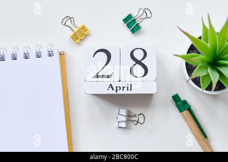 Date sur des cubes de bois blancs - le vingt-huitième, 28 avril sur une table blanche. Vue de dessus. Gros plan. Banque D'Images