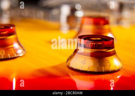 foyer sélectif sur le bouton orange situé sur le dessus d'une guitare électrique flammée de couleur cerise Banque D'Images