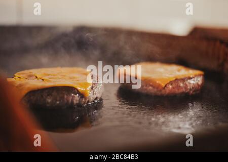 Frire les cheeseburgers sur le gril tout en fumant Banque D'Images