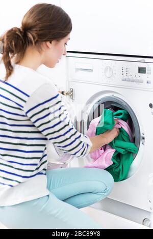 Femme mettant sa blanchisserie dans un lave-linge Banque D'Images