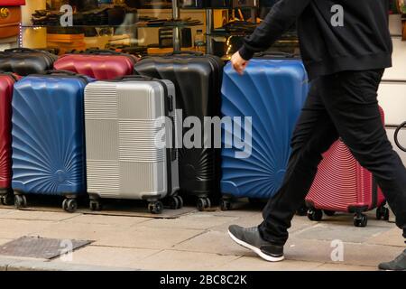 Valises à vendre devant le magasin. Différentes tailles, couleurs et tailles. Les valises sont alignées dans la rue et les gens marchent dans la rue. Banque D'Images