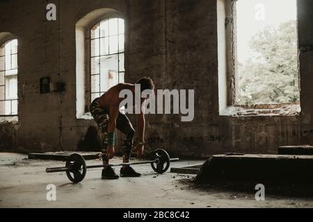 Homme barbu athlétique commençant à faire une remontée mécanique dans un vieux bâtiment. Belle journée Banque D'Images